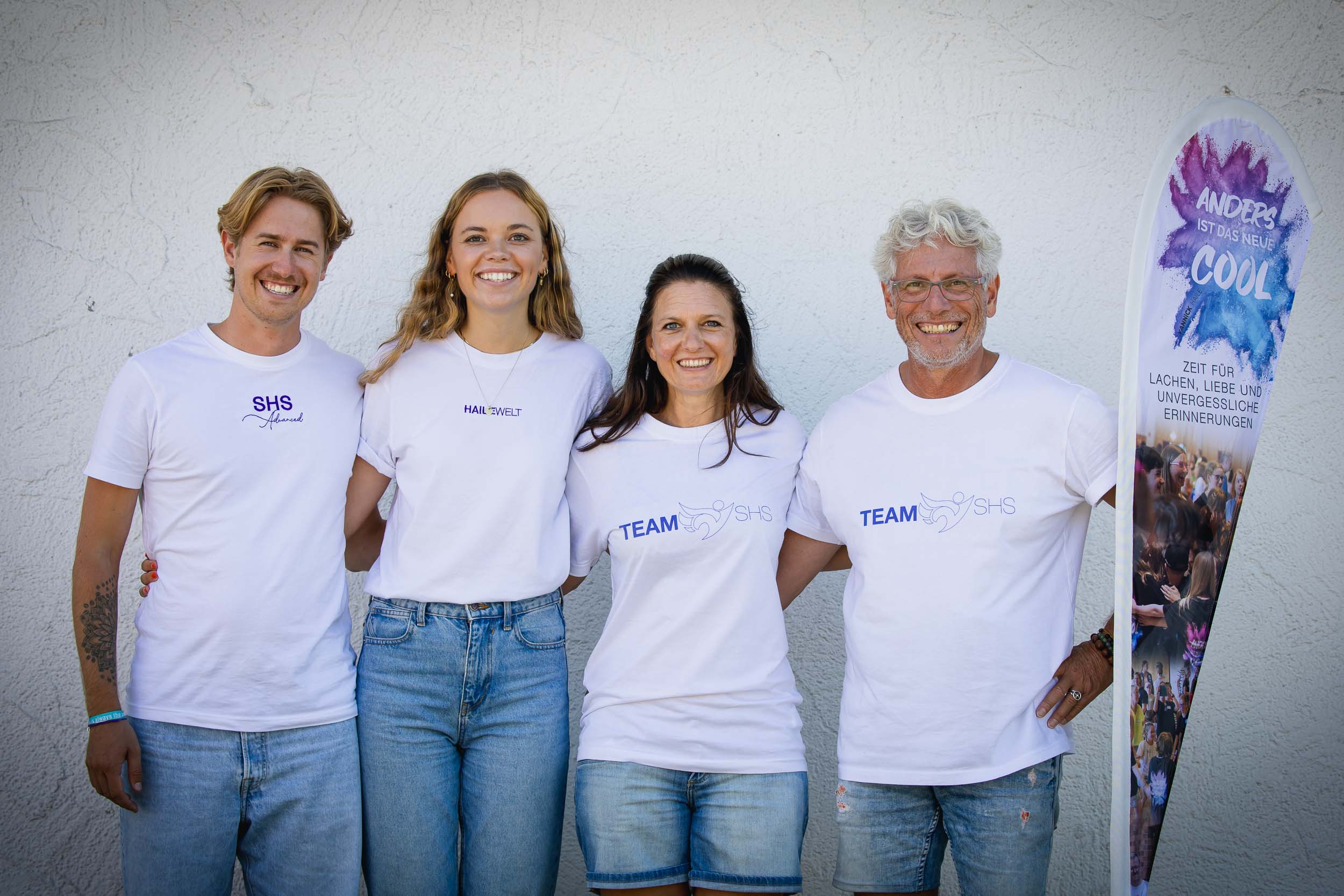 Das Team der Superheldenschmiede neben einem Banner mit dem Motto Anders ist das neue cool